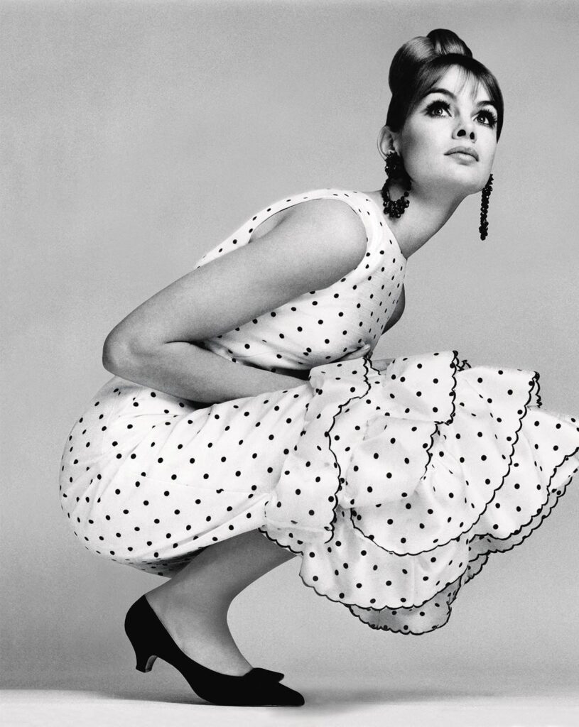 Ancienne photo d'une femme accroupie avec une robe à pois blancs